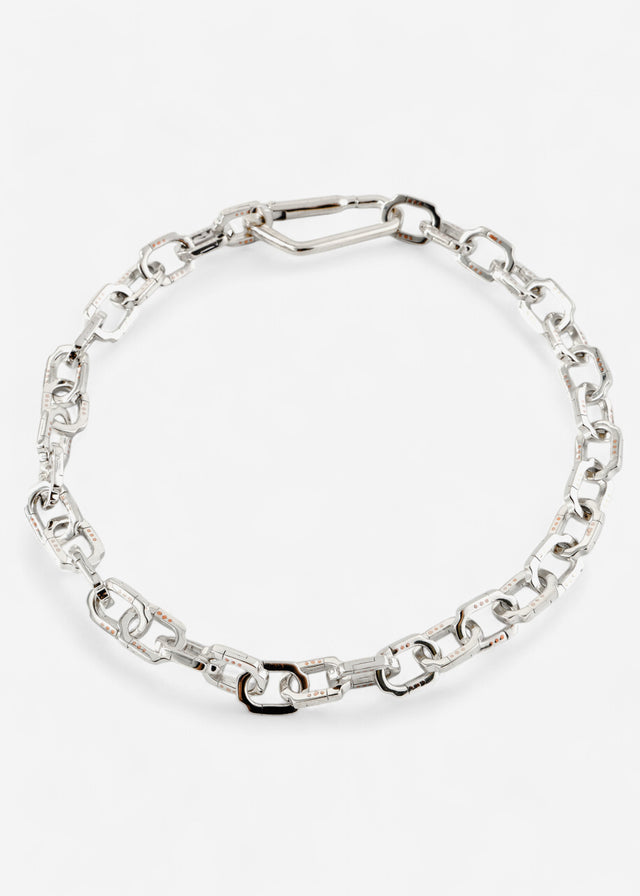 Polished silver chain choker with faceted rectangular links, coiled in a circle on white, overhead studio shot — STRUGA