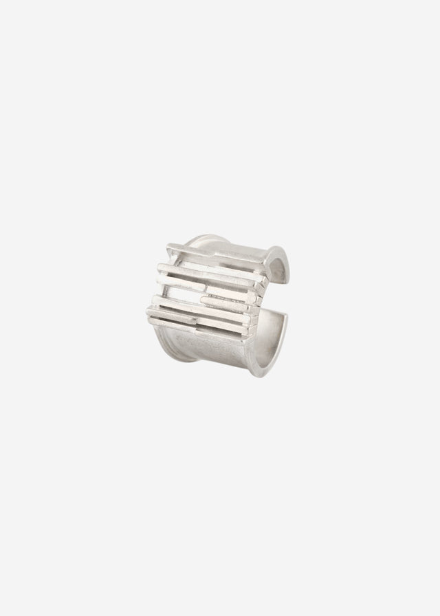 Open silver Brutalism ear cuff with stacked horizontal bars, laid on a pale ground — STRUGA