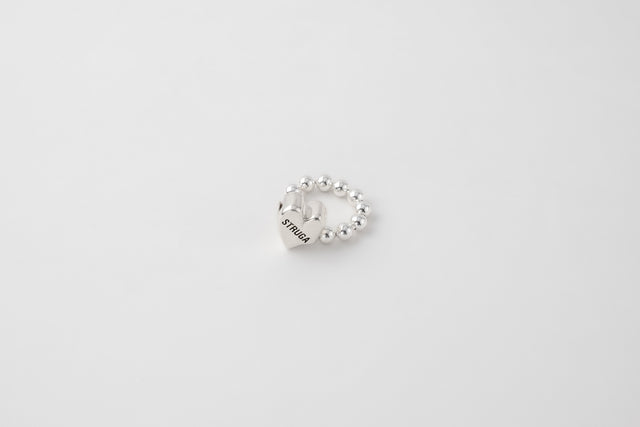 Silver ring with a heart-lock clasp form on a dark surface — STRUGA commission