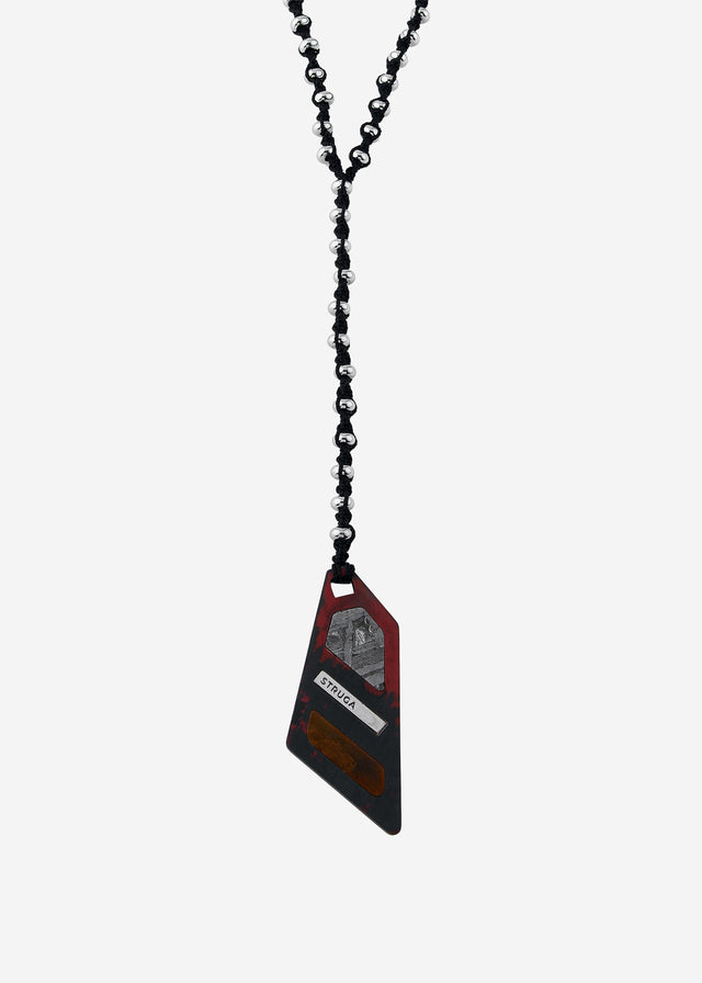 Angular black-and-red pendant, grey crystalline and warm brown inlays, black cord with silvery beads, studio shot — STRUGA