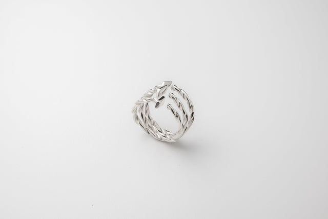 Open triple-band silver ring with twisted drill-bit spirals and flat cut ends, on pale grey studio backdrop — STRUGA