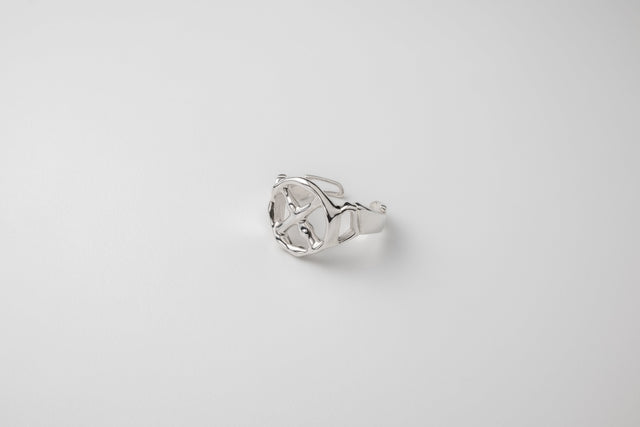 Silver ring with a cast cross set inside a round face, laid on a pale ground — STRUGA