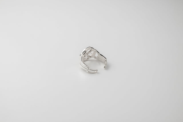 Silver ring with a fused openwork top turned away, wide open shank, on a plain pale grey studio ground — STRUGA