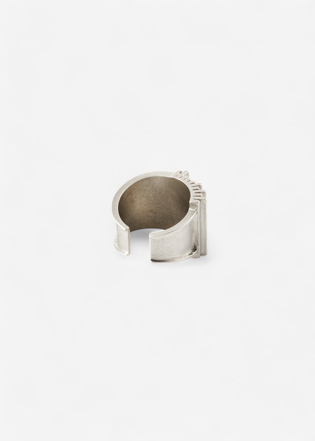 Open silver Brutalism cuff from the back, hand-finished edges and ribbed spine, pale ground — STRUGA